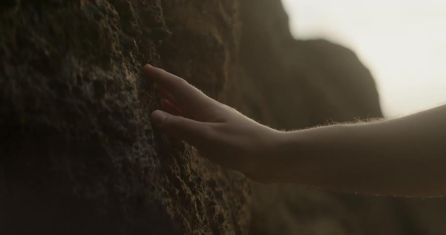 Person is running their hand against a large boulder
