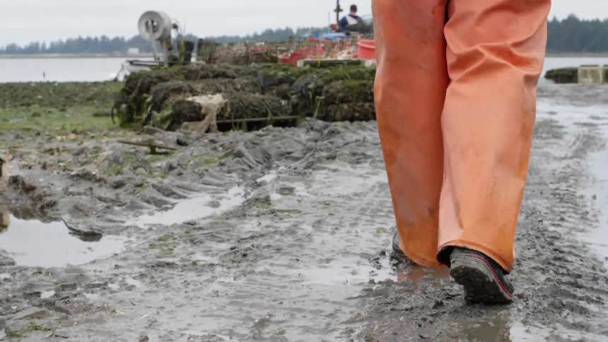 Man in orange jumpsuit walks through the mud