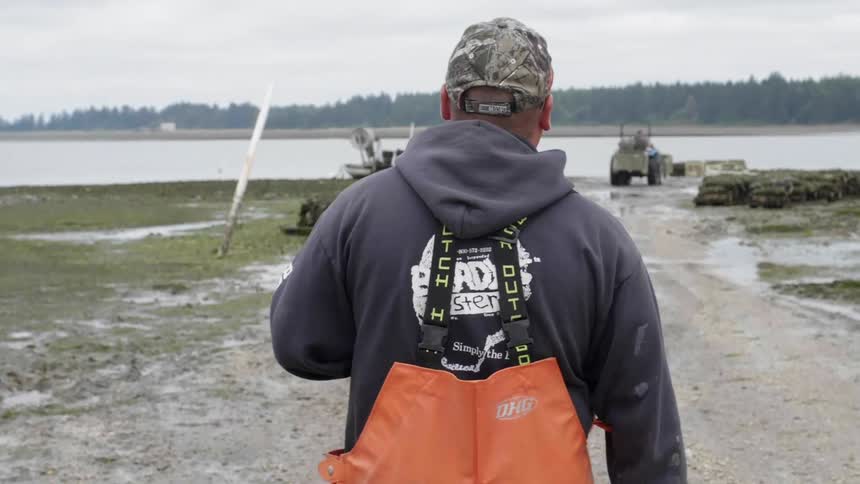 Man wearing orange overalls walks towards a body of water
