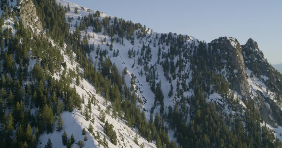 Mountain slopes and ridge covered with trees and snow on a sunny day