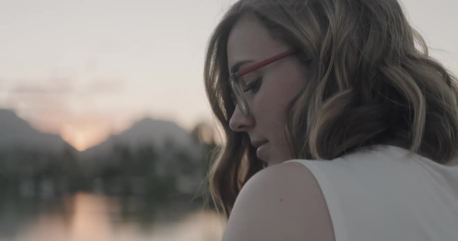 Woman standing near a lake at sunset