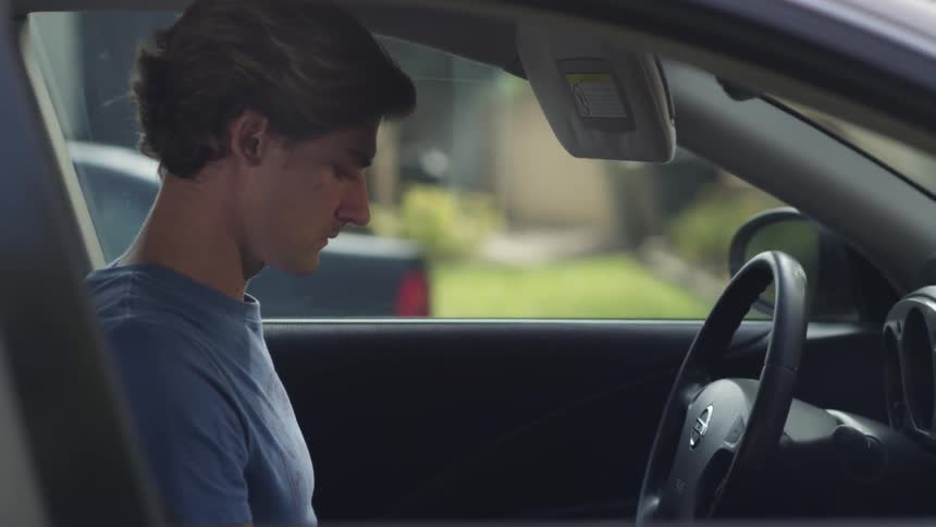 A man getting into his car and dropping the visor