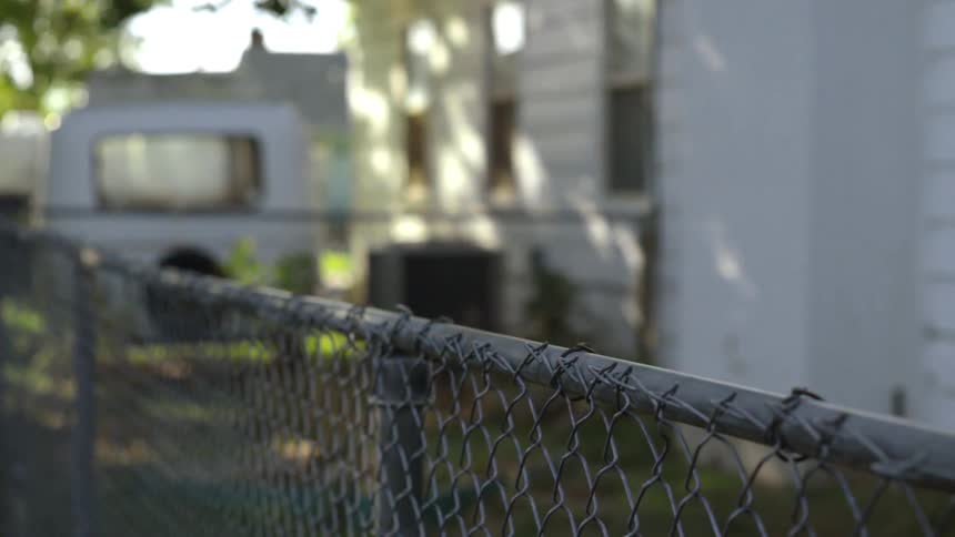 Man jumps a chain link fence on a sunny day