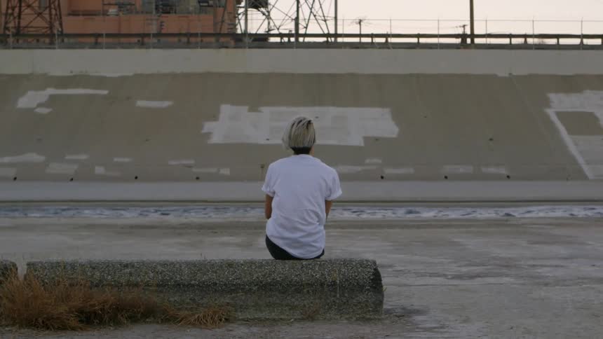 Girl sitting on a concrete stoop watches water pass