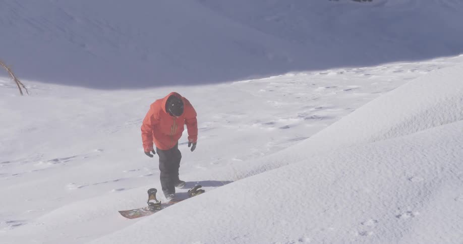 A man with a snowboard in snowy mountains