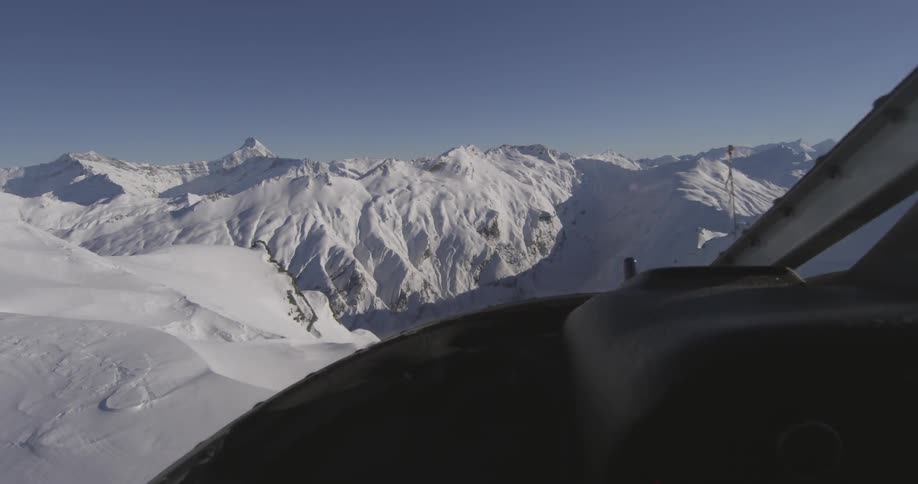 A helicopter is flying to the summit of a mountain