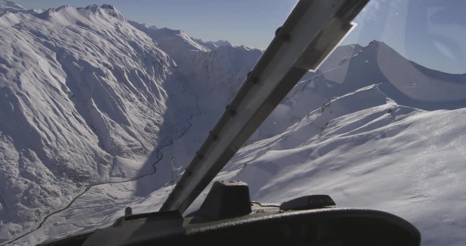 A helicopter flying by snowy mountains
