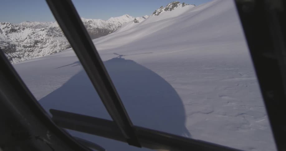 A helicopter lands on the side of a snowy mountain
