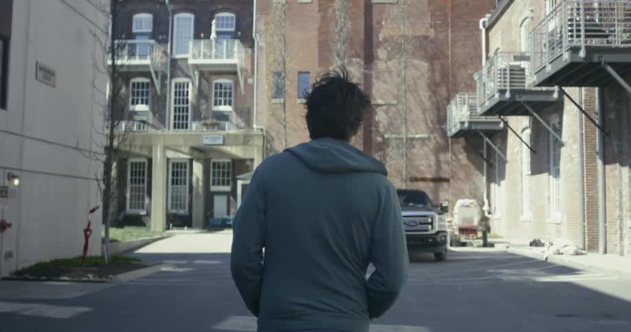 Person walks in a parking lot towards an apartment building