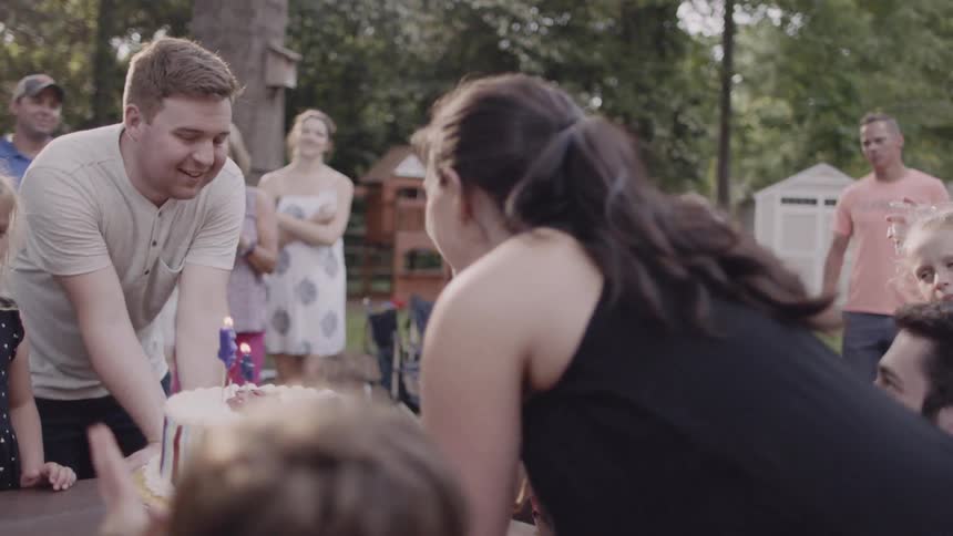 Woman presents a birthday cake to a young boy