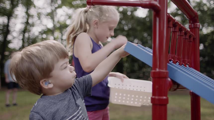 Young children play in a playground near the trees