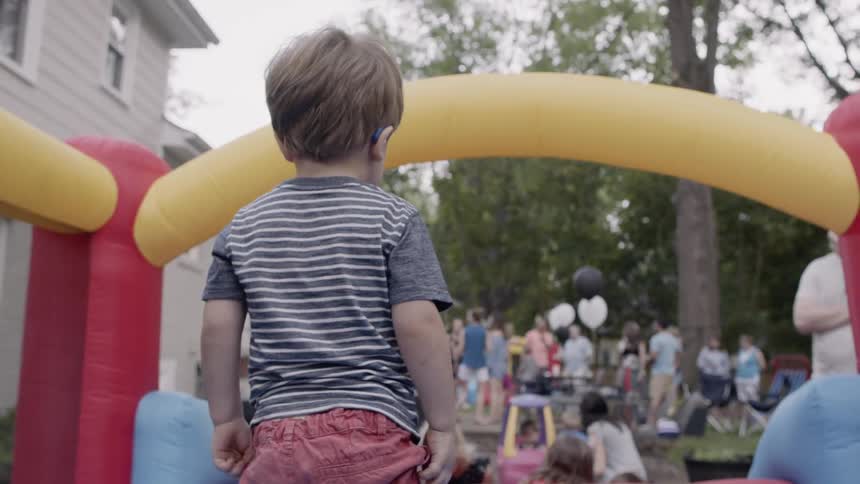 Children jump on a bouncy house at an outdoor party