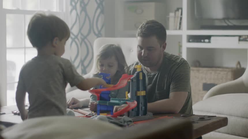 Man and two young toddlers play with a toy