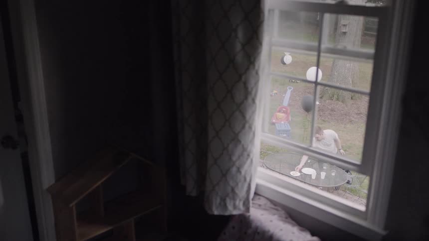 A man in the backyard cleaning up after a party is visible through the window
