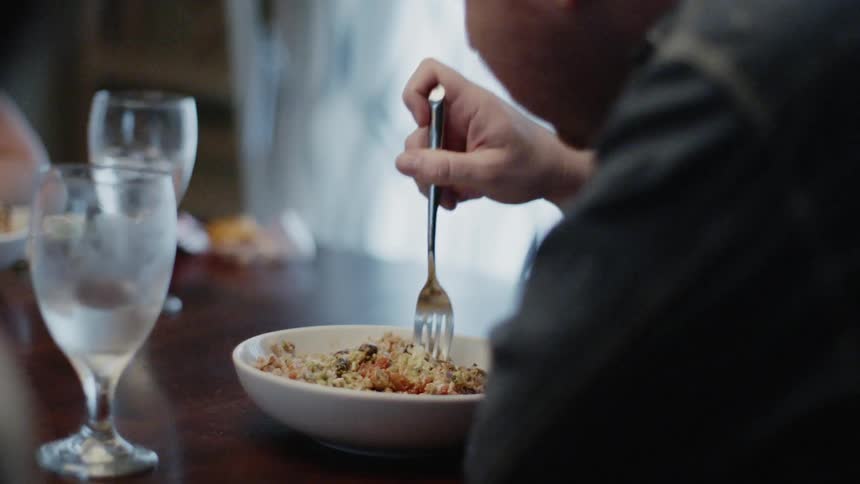 Man pushes food around on a plate with a fork before he eats it