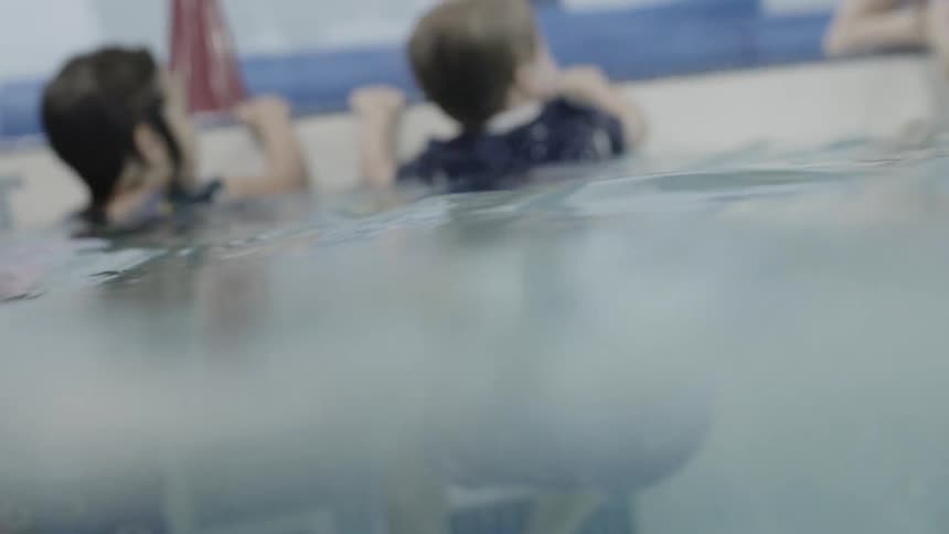 Children hang on the side of the pool