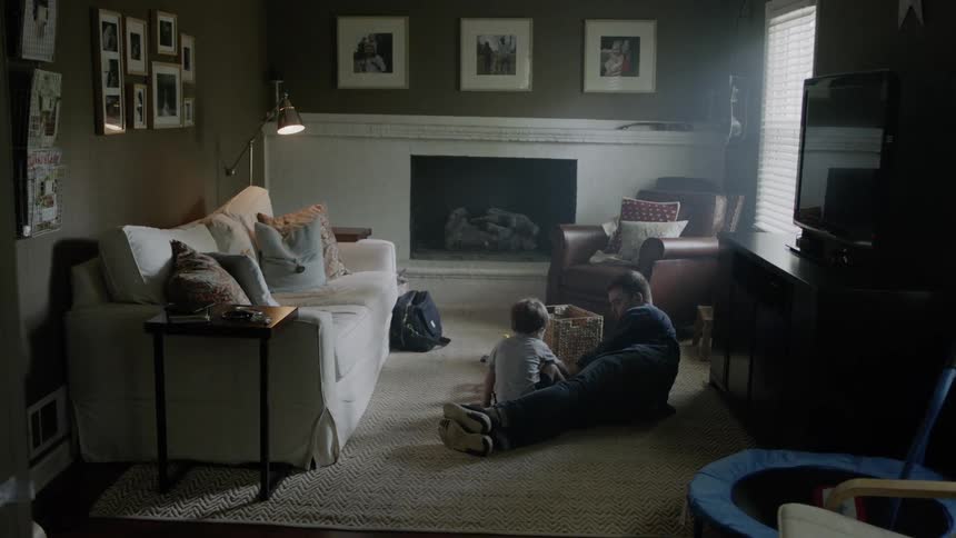 Man and young boy play with toys on a living room floor