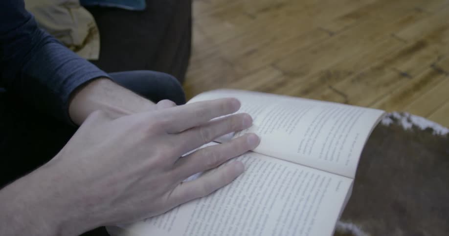 A person reads from a book on the couch