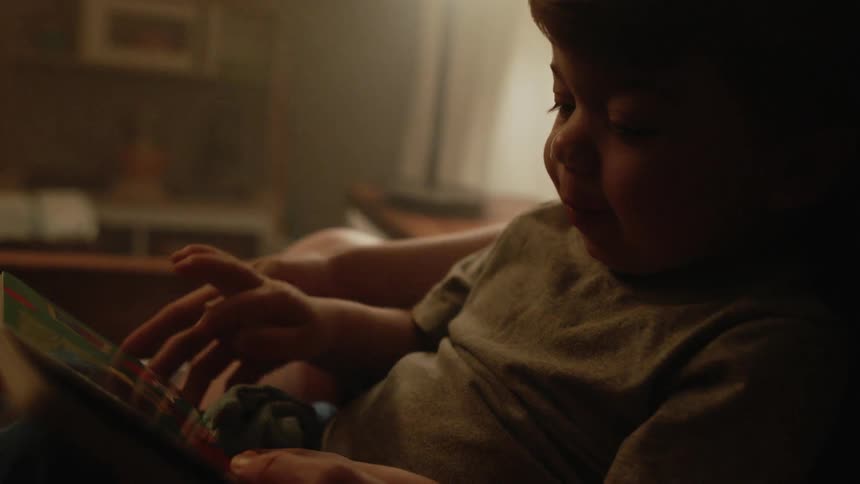 A parent and young child read a book together