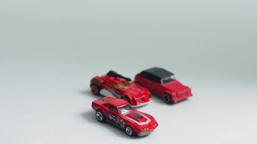 Three red toy cars sit on a floor
