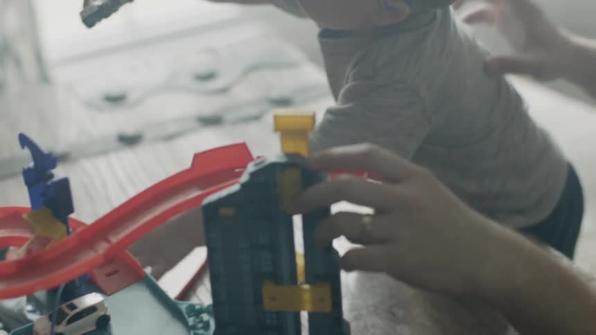 Child and man play with toy cars on a race track