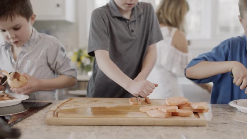 Young boys peel and cut potatoes in a kitchen