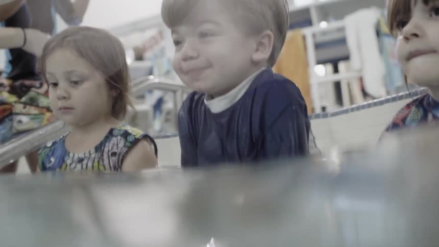 Young children sit in a swimming pool