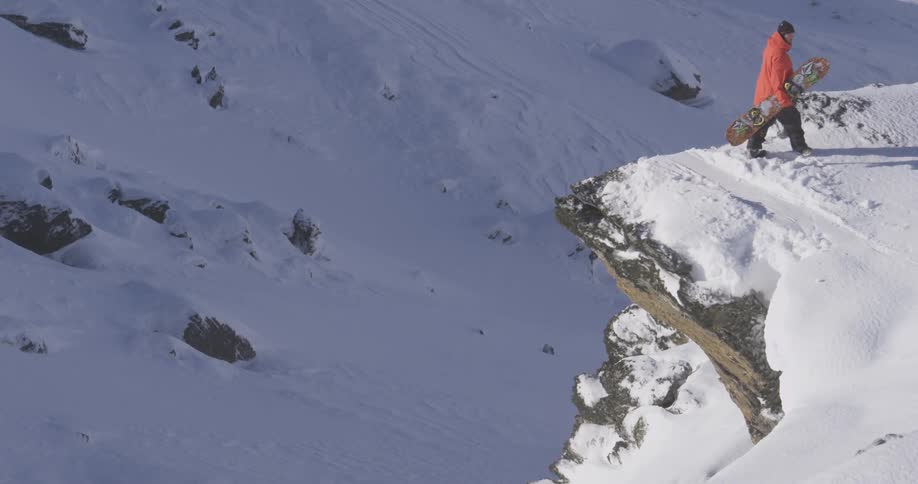 Man with snowboarding standing by cliff