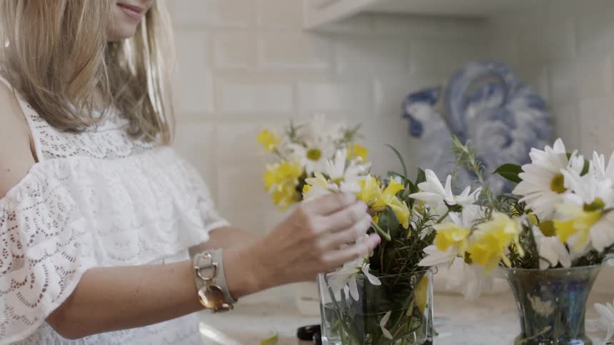 A woman places flowers in a vase