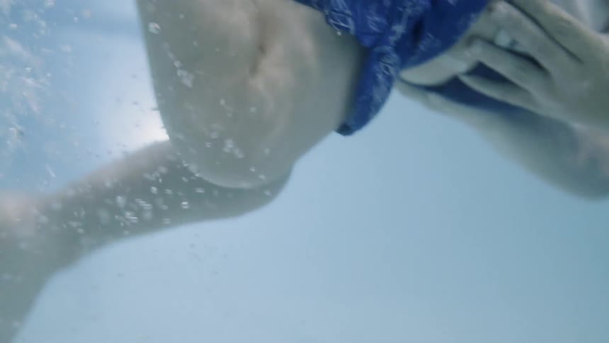 Woman holds a young boy while he swims in a pool