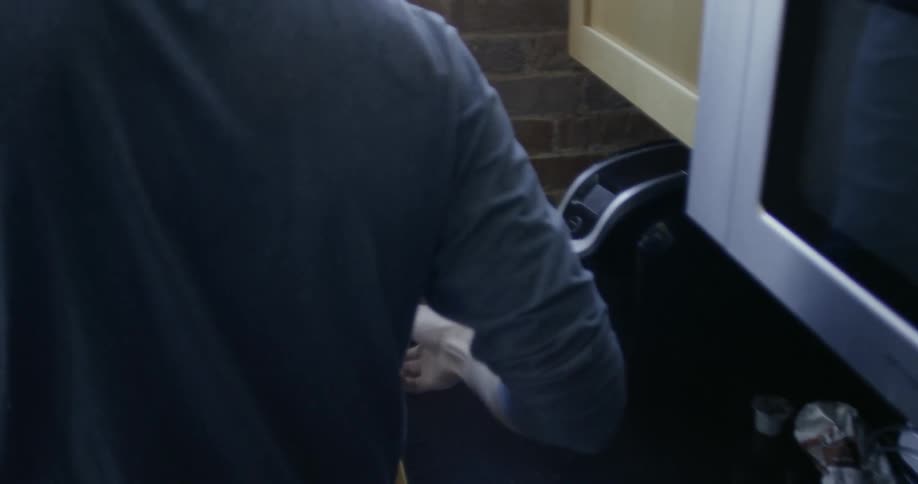 Man picks up cup of coffee from coffee machine in kitchen