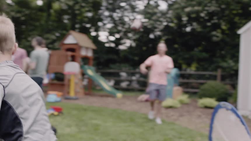 Child throws a football to a man in a backyard