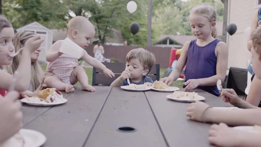 Children eat cake at an outdoor birthday party