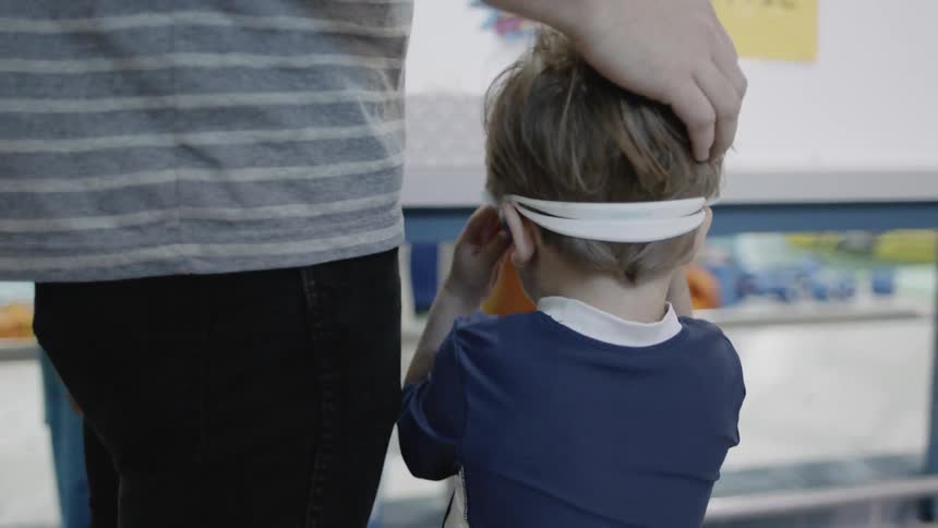 Young boy wears swimming goggles next to a pool