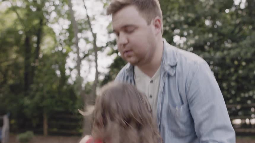 A man is getting his child off a large swing
