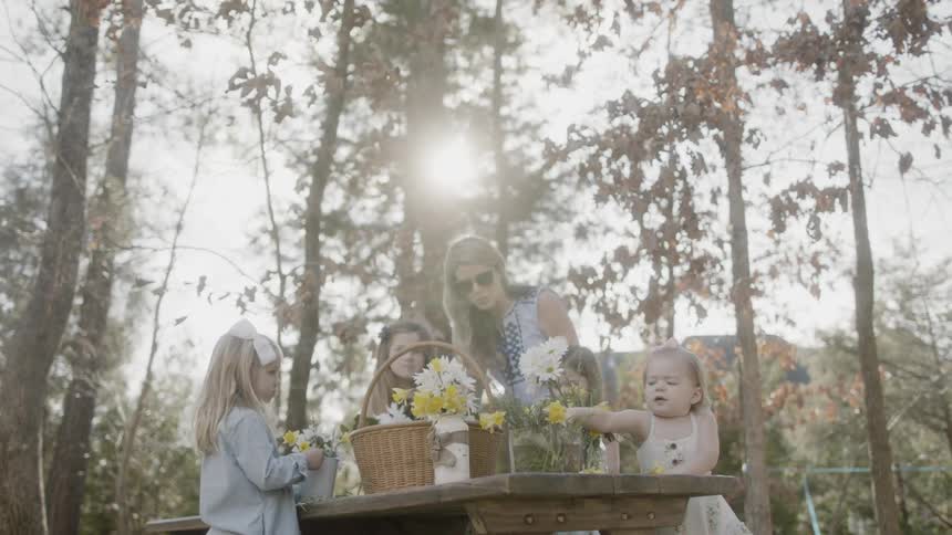 A woman builds flower bouquets with young girls