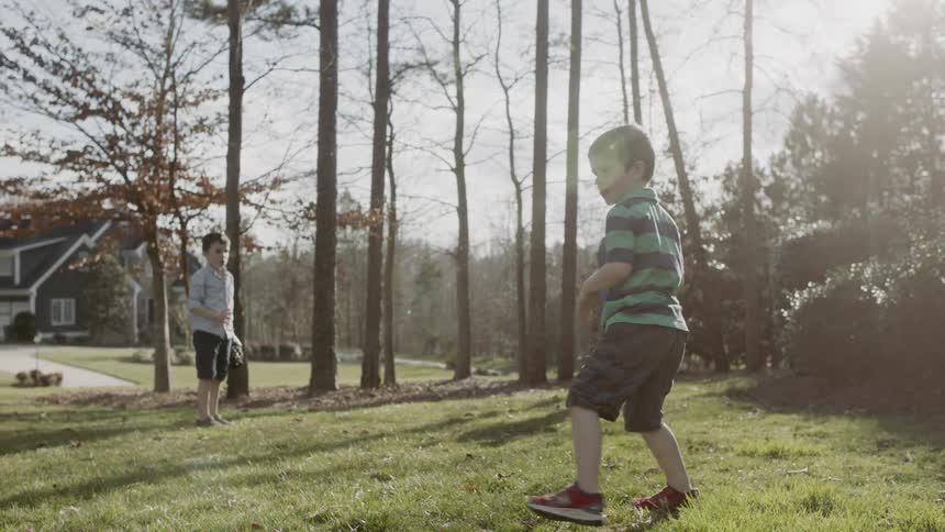 The child throws the football in the yard