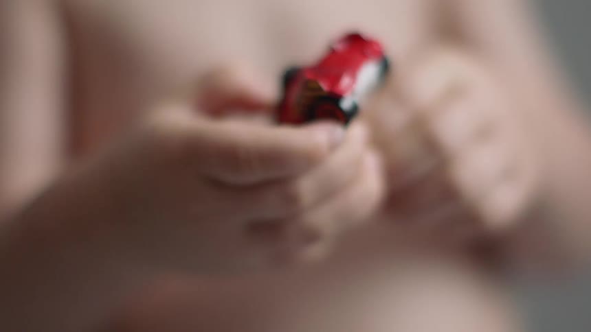 A boy is playing with a toy car inside in daylight