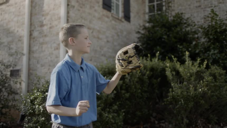 A little boy is throwing a baseball around with someone