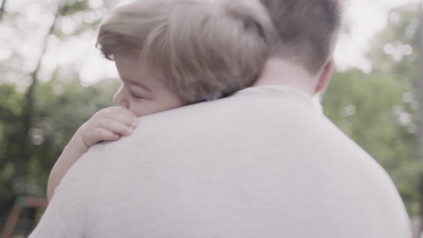 Young boy rests on father's shoulder