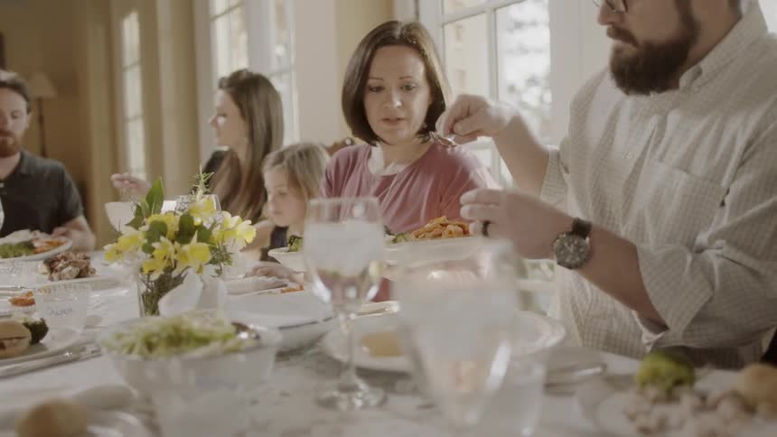 Family is having dinner at table in sunny dining room