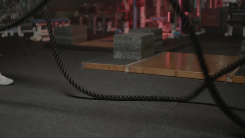 A man works out with the heavy rope in a gym
