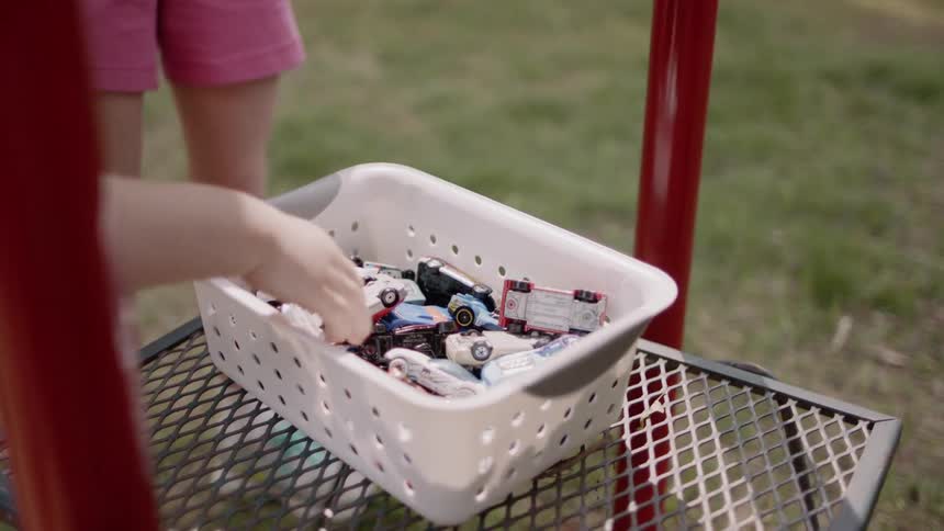 Kids are digging through a basket of toy cars