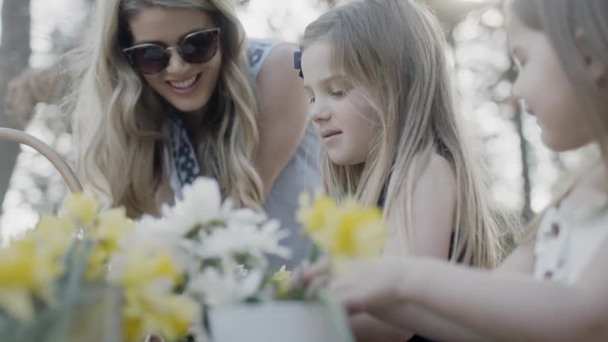 The woman laughs with the children as they arrange flowers