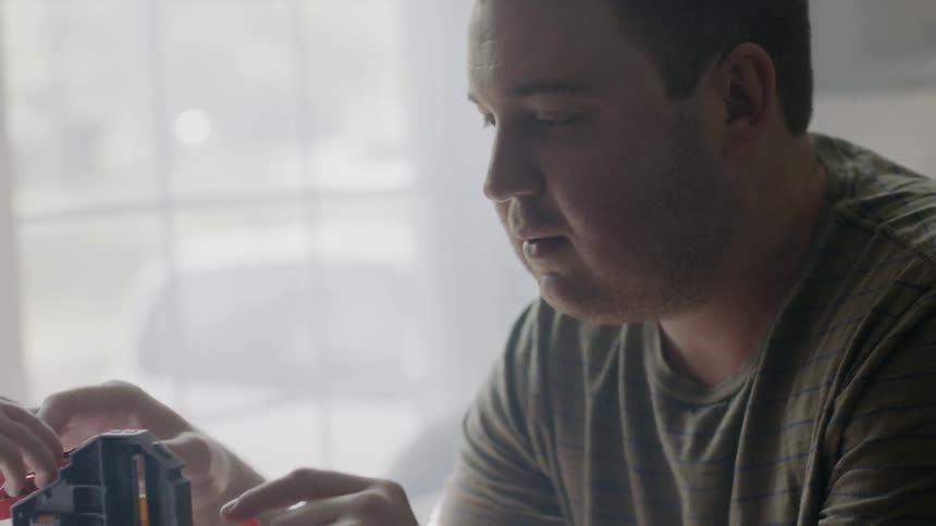Man touches some toys as he sits near the window