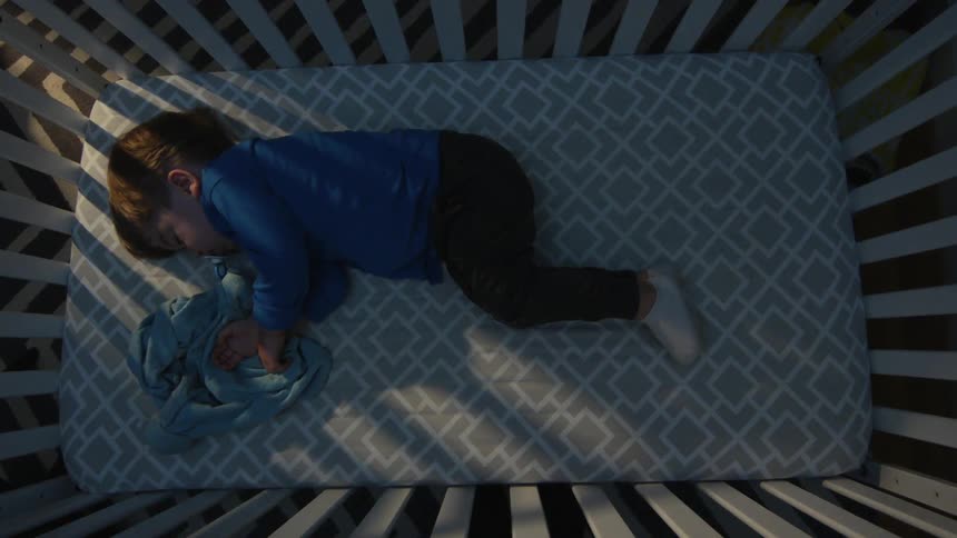 A toddler sleeps in their crib