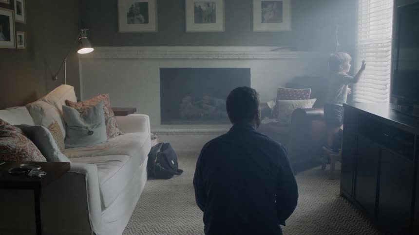 Father and boy in living room as boy looks out window