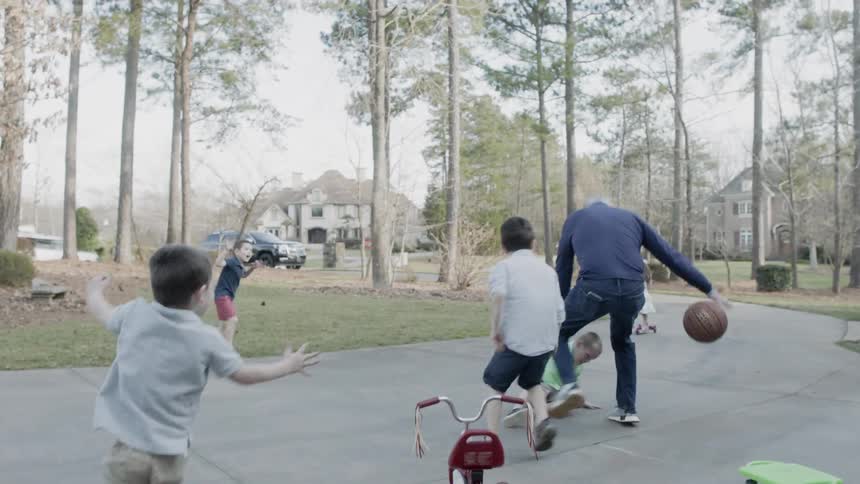 A man plays basketball with a group of children