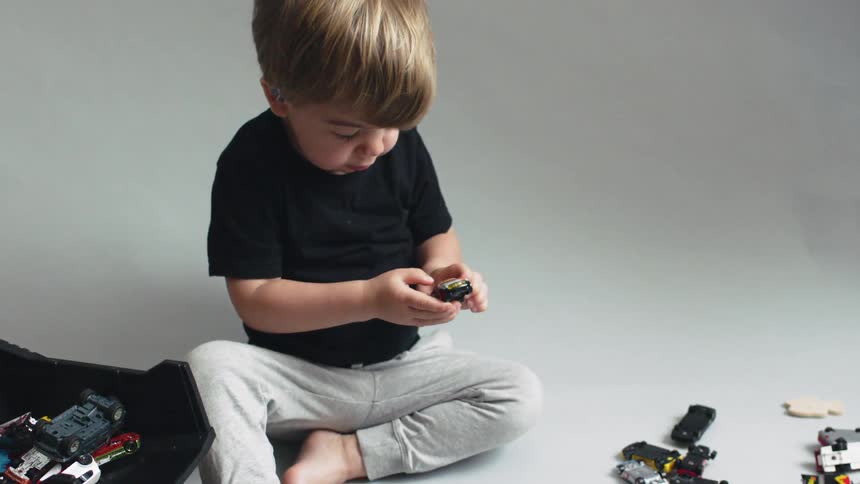 Young boy plays with toy cars on a floor