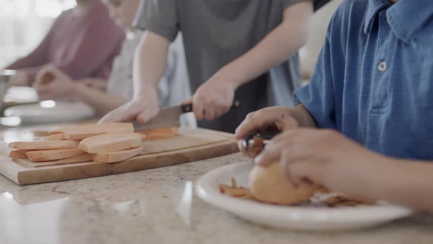 Boys peel and cut potatoes in a kitchen